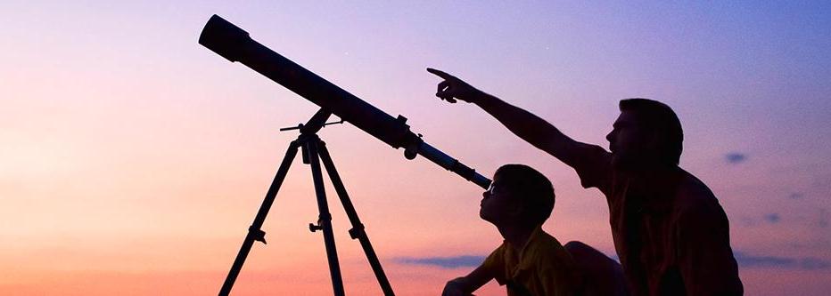 Man and son looking through telescope at dusk